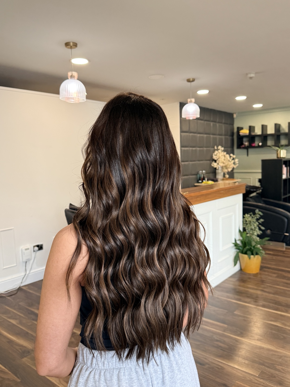 Long glossy brunette waves finished with soft movement, photographed from behind at iHobbs.