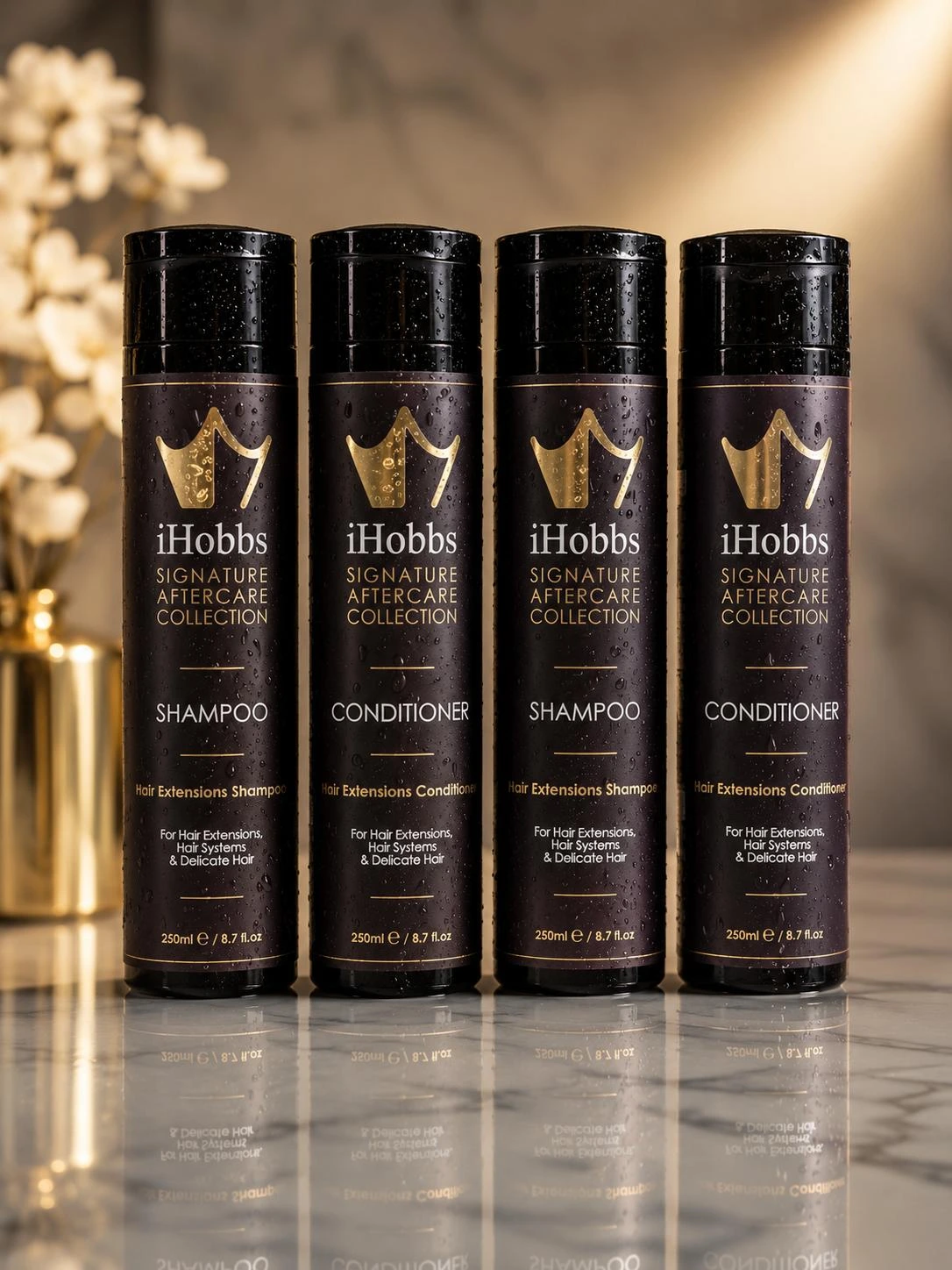 Four iHobbs Signature Aftercare bottles on marble: two Hair Extensions Shampoos and two Hair Extensions Conditioners, with their front labels visible