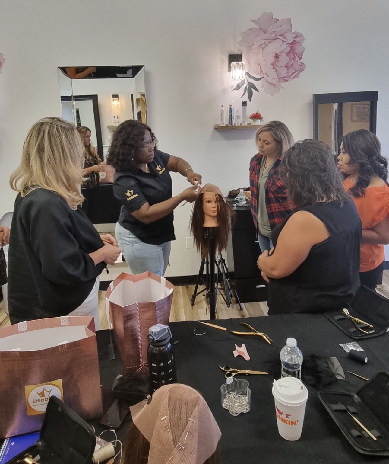 A mesh integration technique being demonstrated on a mannequin head at an iHobbs Academy training session, with students observing around the table.