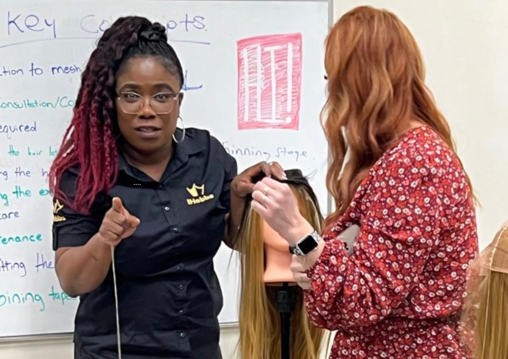 Sandra Atoge demonstrating a hair replacement technique to a student using a training mannequin during a practical iHobbs Academy session.