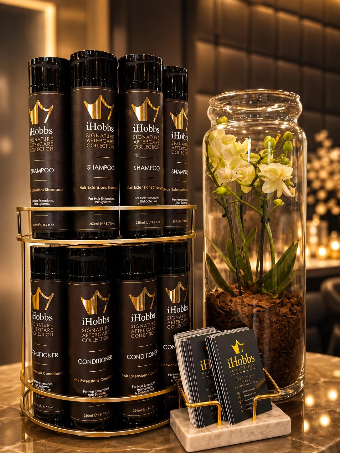iHobbs Signature Aftercare Shampoo and Conditioner displayed in the salon on a gold stand beside flowers